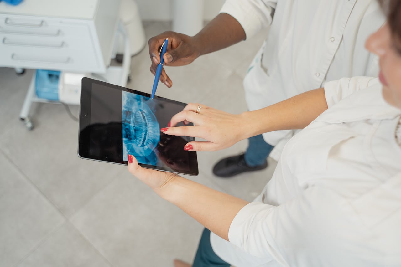 Dentist examining a dental x-ray on a tablet with patient in a modern clinic.